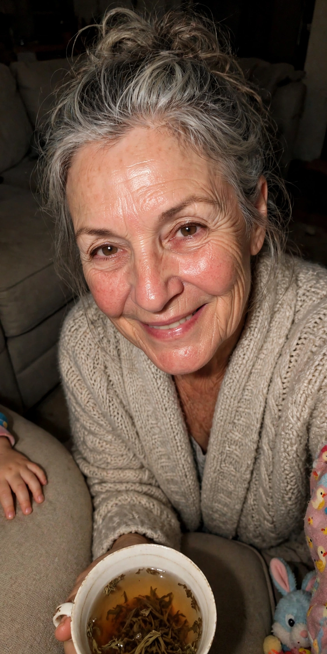 Auntie June on her couch in dim flash light, holding a teacup